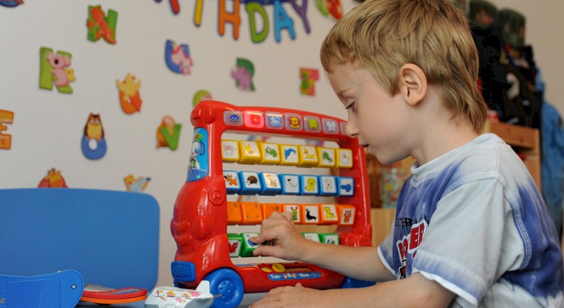 Ein Kind spielt mit einem Lernspielfahrzeug mit Bildtafeln.