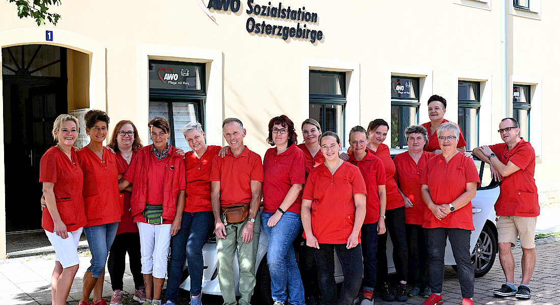Teamfoto mit zahlreichen Personen in roten Shirts vor einem hellen Gebäude mit AWO-Logo.
